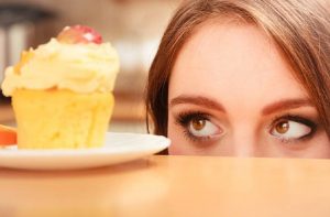 femme regardant un petit gâteau avec du glaçage