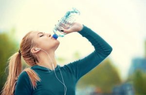 une femme boit de l'eau dans un verre